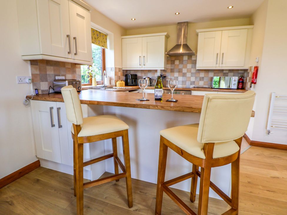 A kitchen with bar stools and a countertop at The Brambles in Holt, North Wales