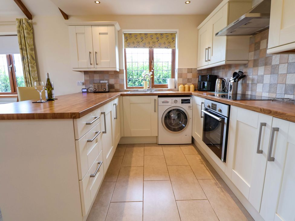 A kitchen with washing machine, oven, and sink at The Brambles in Holt, North Wales