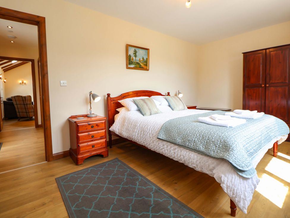 A bedroom with a bed, bedside table, and wardrobe at The Brambles in Holt, North Wales