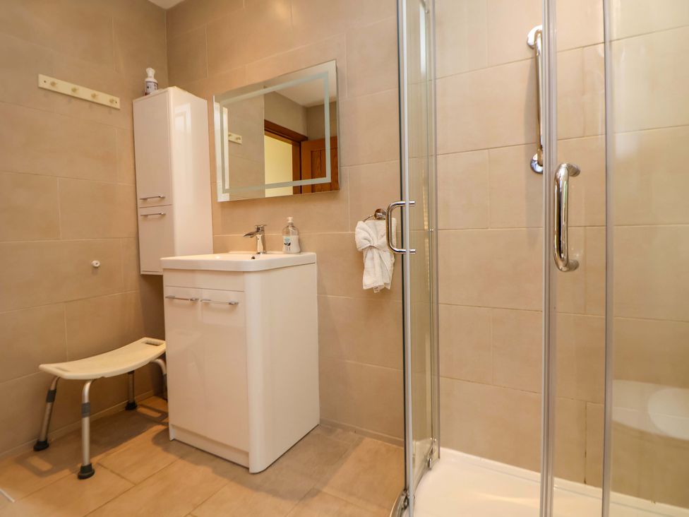 A bathroom with a sink, mirror and shower at The Brambles in Holt, North Wales