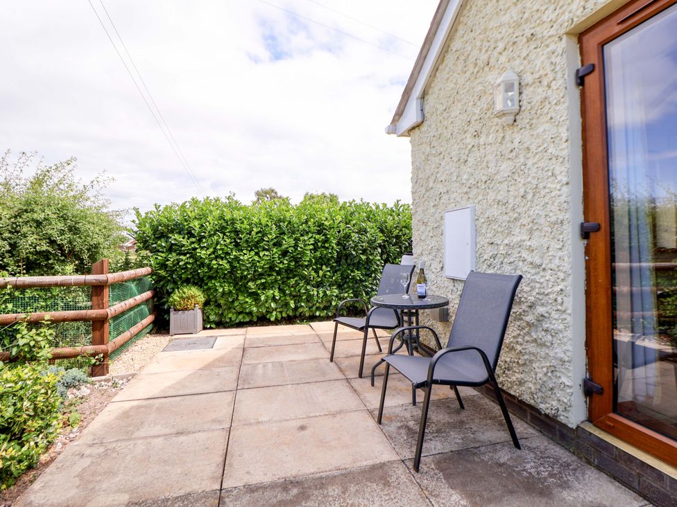 A patio area with a table and chairs at The Brambles in Holt, North Wales