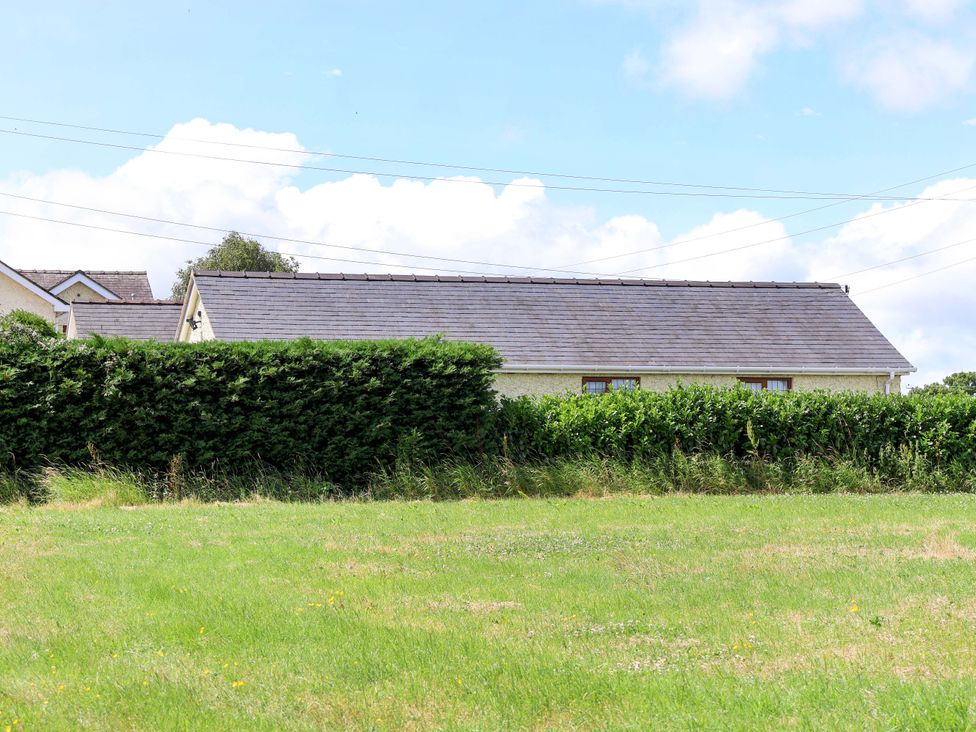 A house with a hedge and grass at The Brambles in Holt, North Wales
