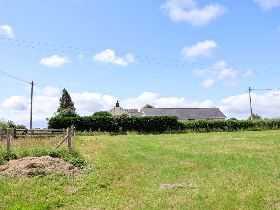 A field with a house in the background at The Brambles in Holt, North Wales