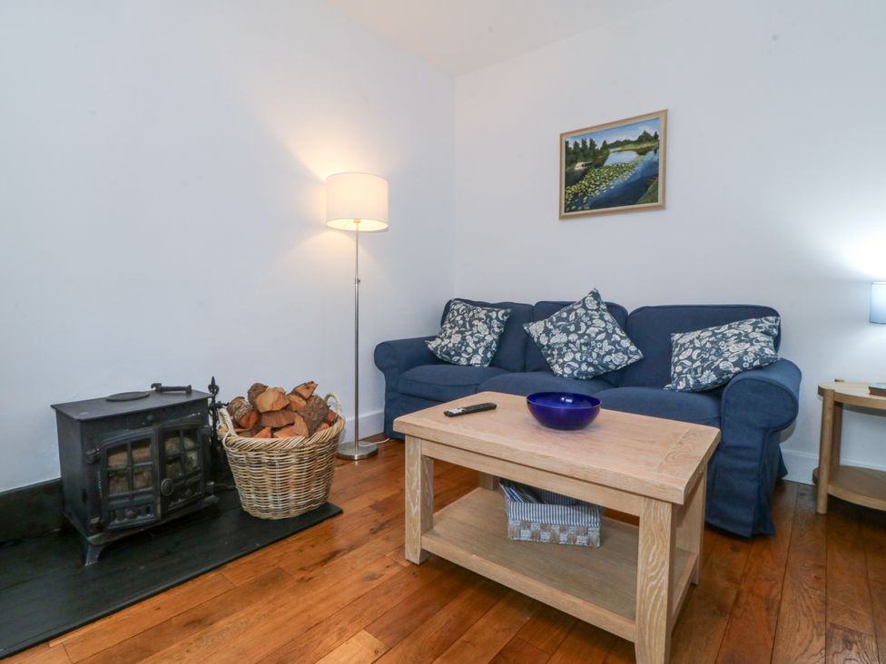 A living room with a sofa, coffee table, and wood stove at Ty Capel Bethania Nant Gwynant
