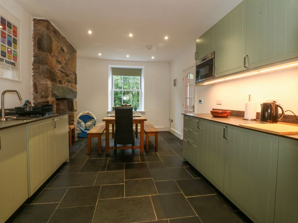 A kitchen with cabinets and dining table at Ty Capel Bethania Nant Gwynant