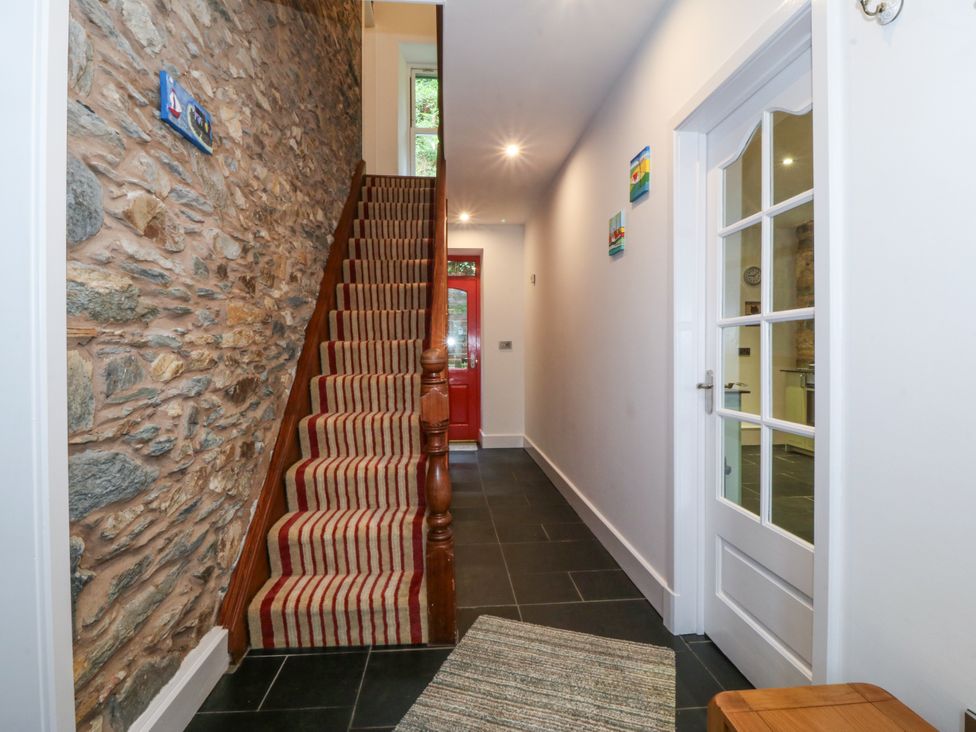A hallway with stairs and a red door at Ty Capel Bethania Nant Gwynant