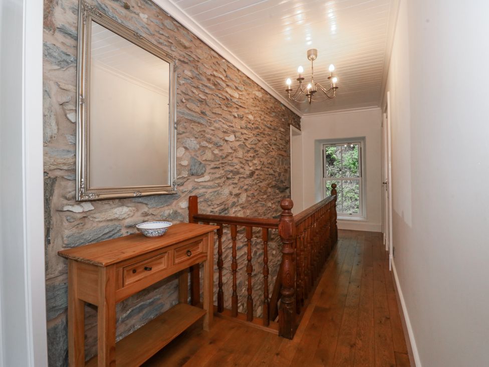 A hallway with a stone wall and a console table at Ty Capel Bethania Nant Gwynant