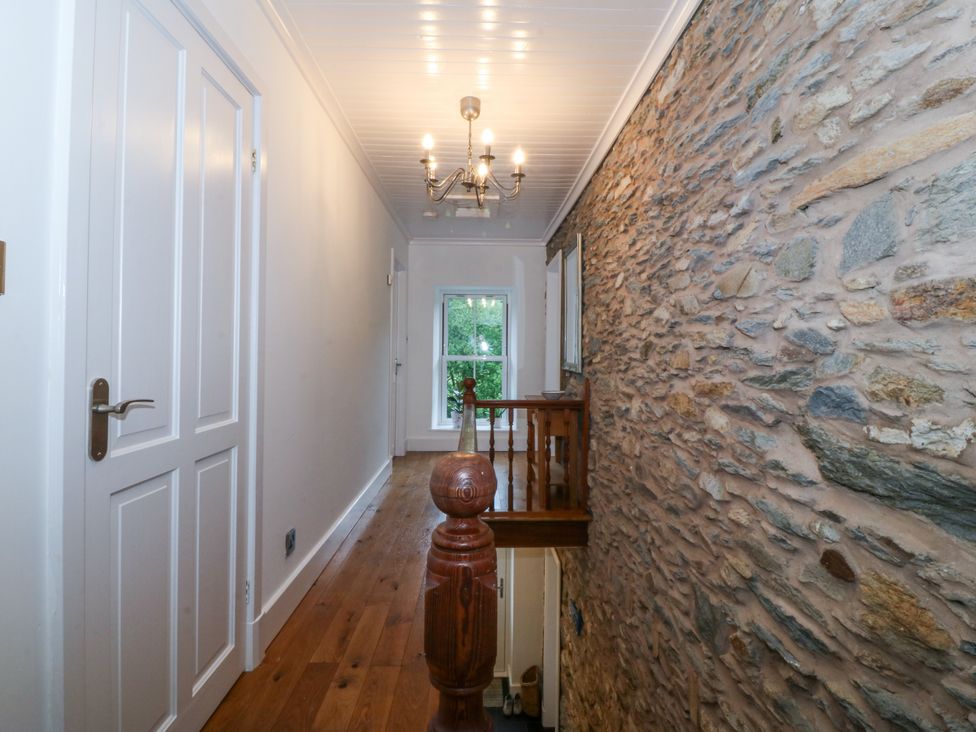 A hallway with a stone wall and wooden railing at Ty Capel Bethania Nant Gwynant