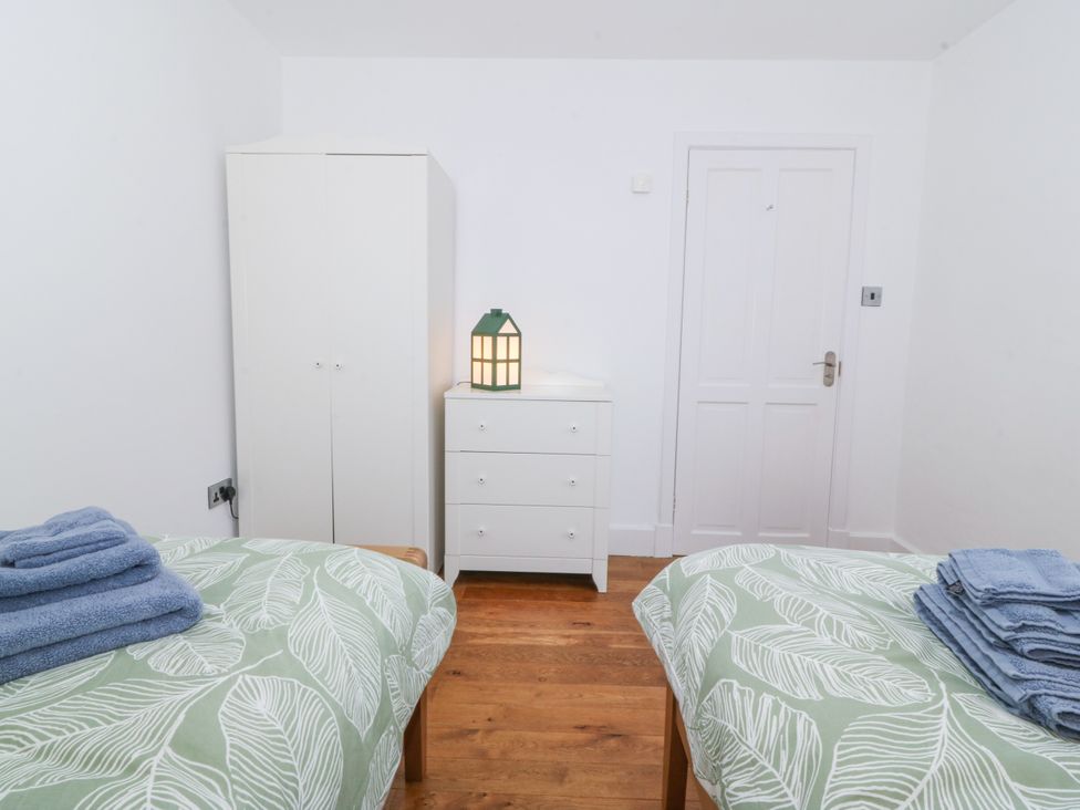 A bedroom with two beds, a wardrobe, and a chest of drawers at Ty Capel Bethania in Nant Gwynant