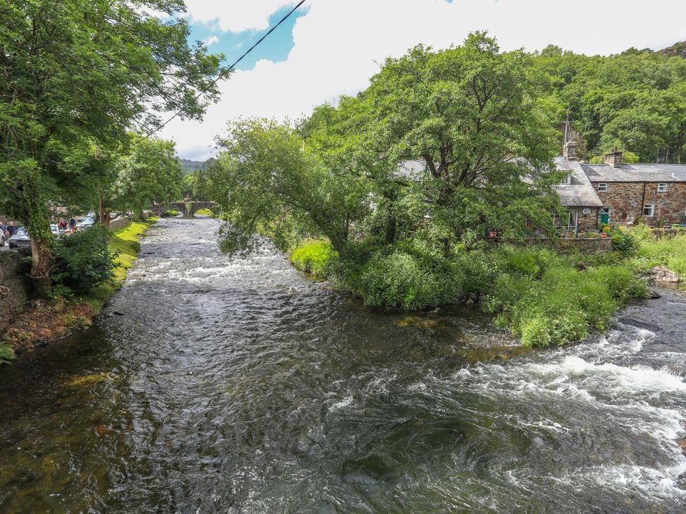 A view of a river and stone house at Ty Capel Bethania in Nant Gwynant