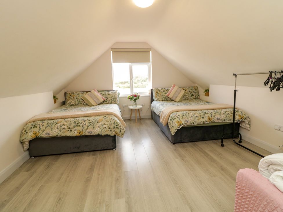 A bedroom with two beds and a small table with flowers at Duffy Lodge Kilmacloo near Creeslough, County Donegal