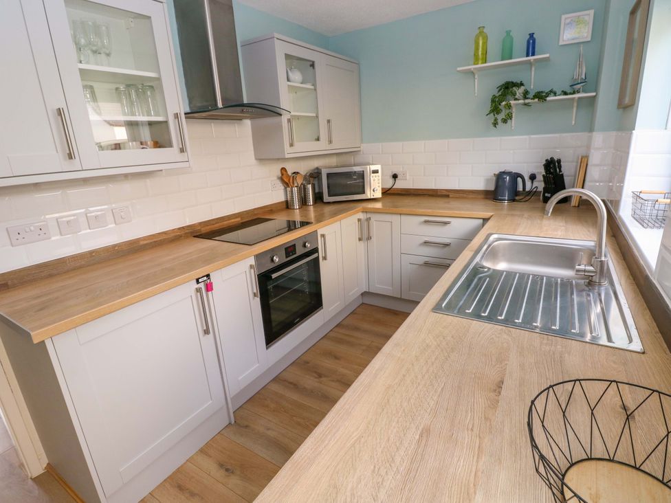 A kitchen with cabinets and appliances at No.22 The Clicketts in Tenby