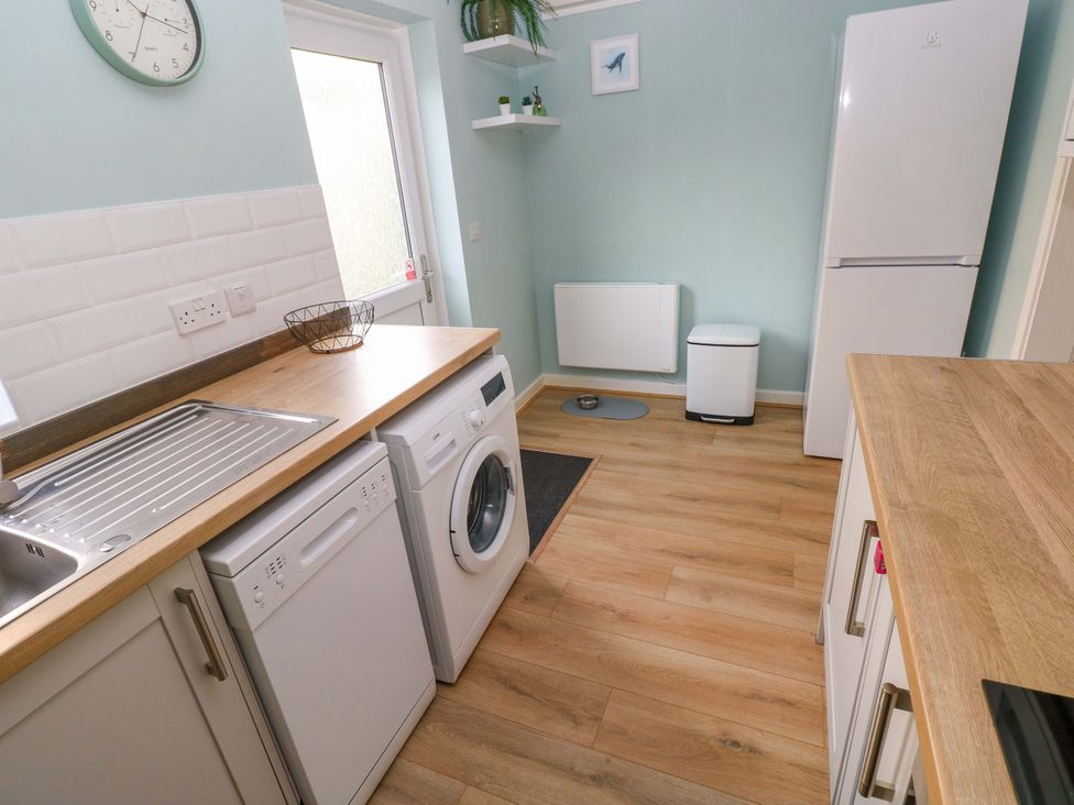A laundry room with a washing machine and a sink at No.22 The Clicketts in Tenby