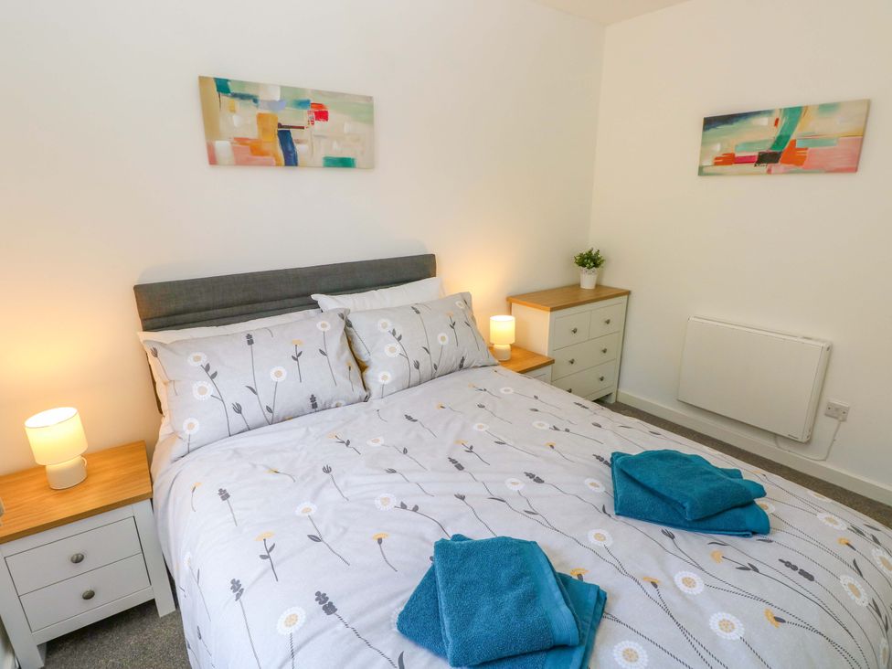 A bedroom with a bed, bedside table, and chest of drawers at No.22 The Clicketts in Tenby