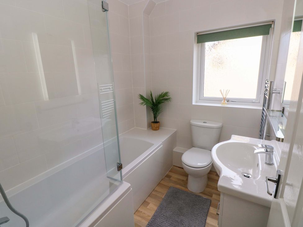 A bathroom with a bathtub, toilet, and sink at No.22 The Clicketts, Tenby