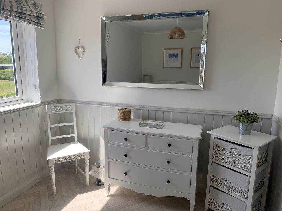 A bedroom with a dresser and chair at Lavender Cottage in Beadnell