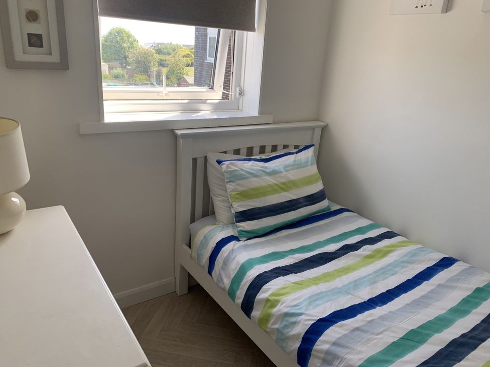 A bedroom with a bed and lamp at Lavender Cottage in Beadnell