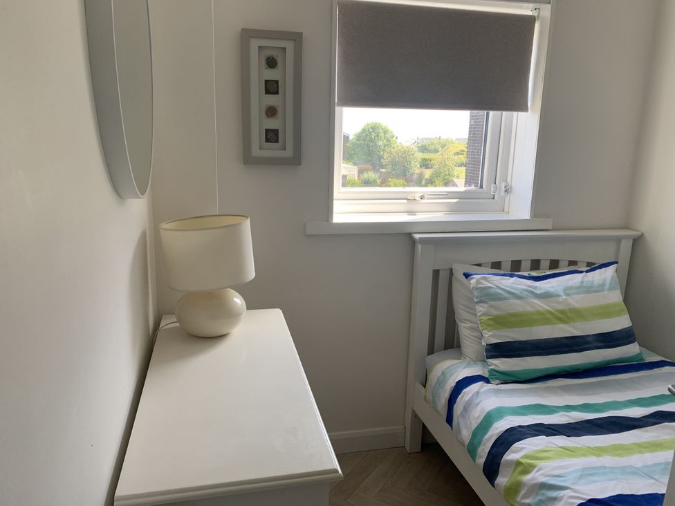 A bedroom with a bed and lamp at Lavender Cottage Beadnell