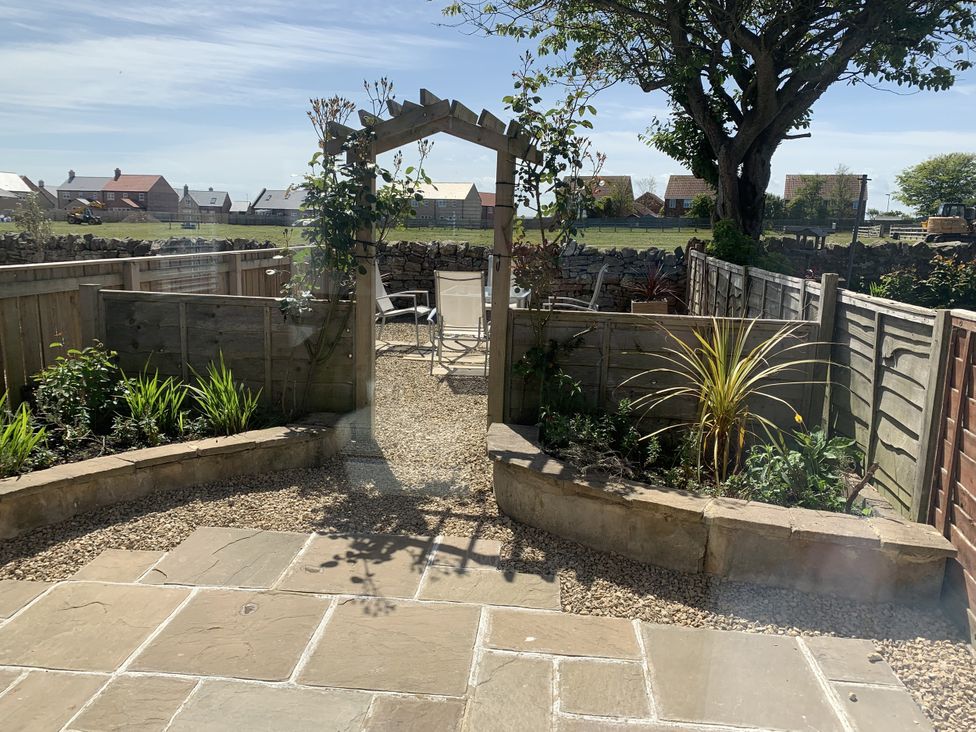 A garden with an archway and gravel path at Lavender Cottage Beadnell