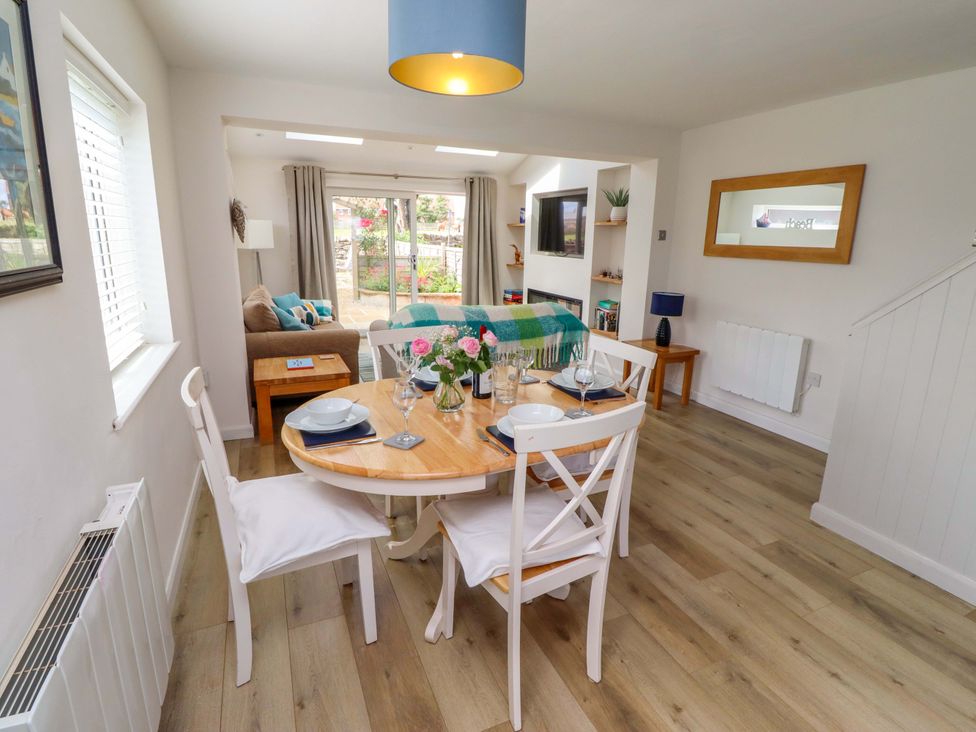 A dining room with a table set for meals and a couch at Lavender Cottage Beadnell