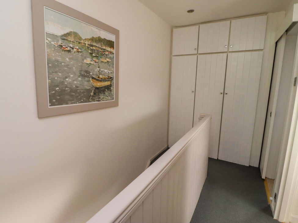 A hallway with a painting and storage cabinets at Lavender Cottage Beadnell
