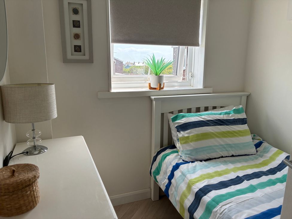 A bedroom with a bed and lamp at Lavender Cottage Beadnell