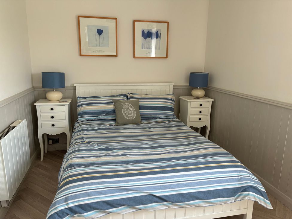 A bedroom with a bed and bedside tables at Lavender Cottage Beadnell