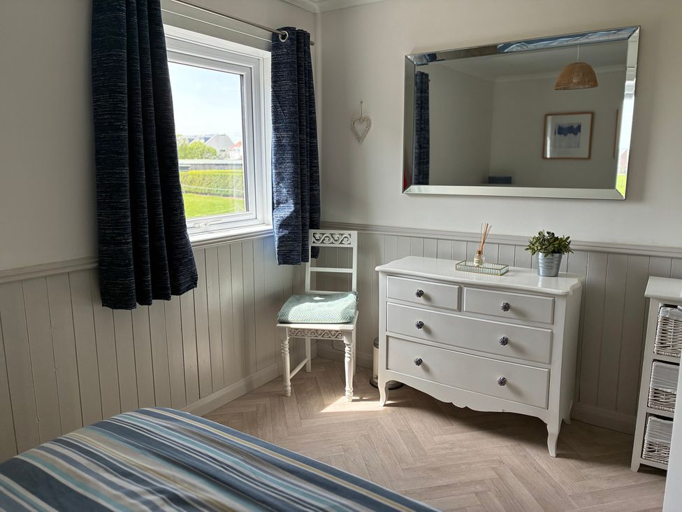 A bedroom with a window and dresser at Lavender Cottage Beadnell