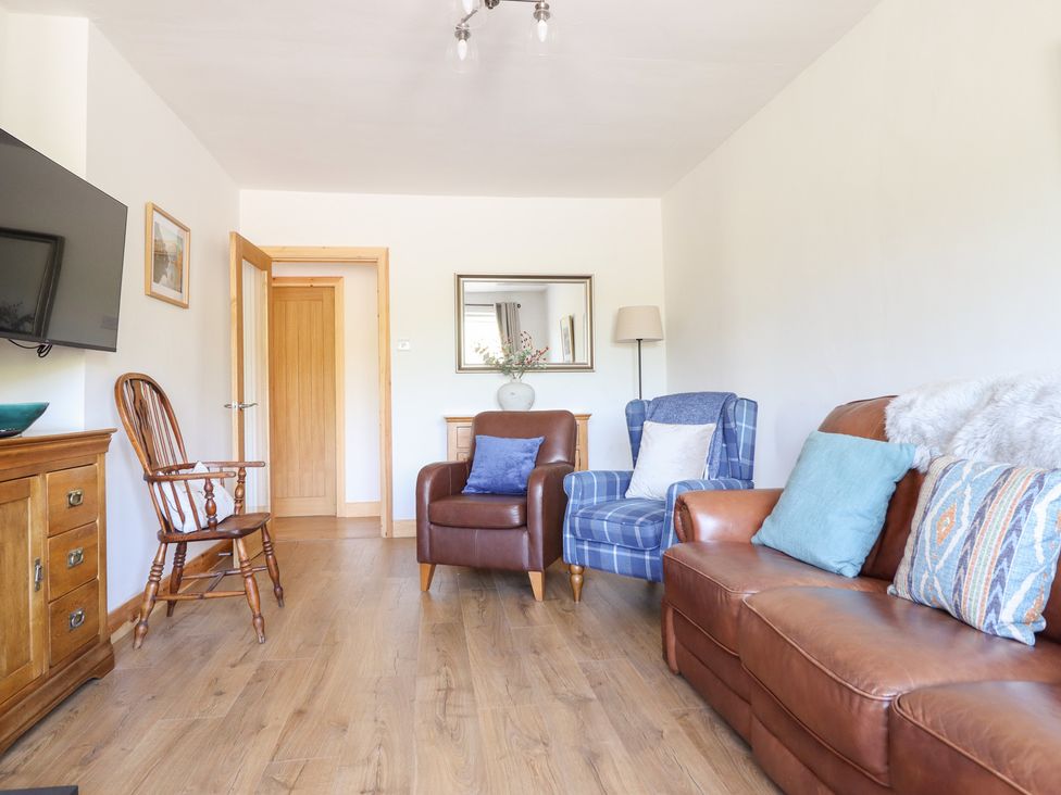 A living room with a television and armchairs at Bryn Bras in Corwen