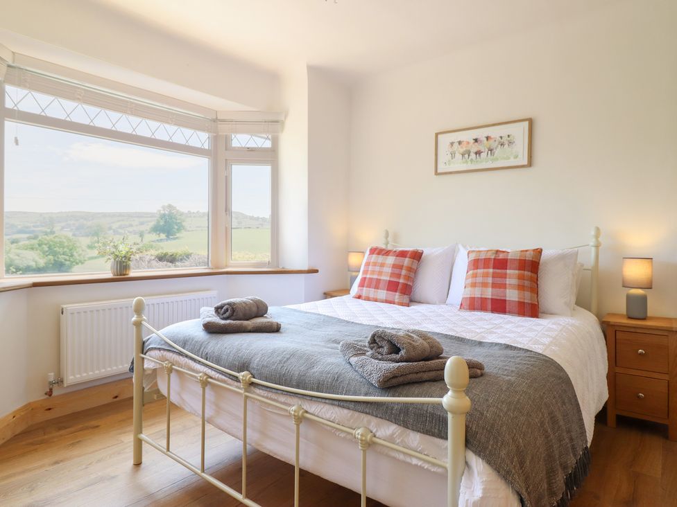 A bedroom with a bed and windows overlooking a landscape at Bryn Bras in Corwen