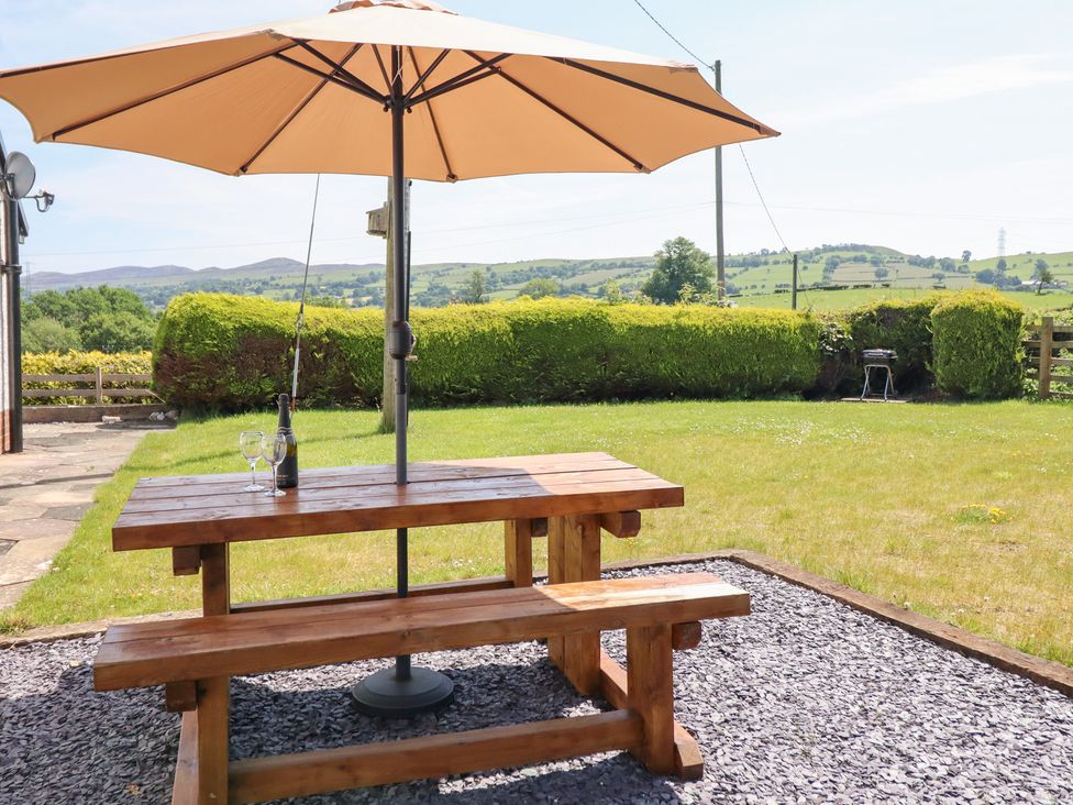 A garden with a table and umbrella at Bryn Bras in Corwen