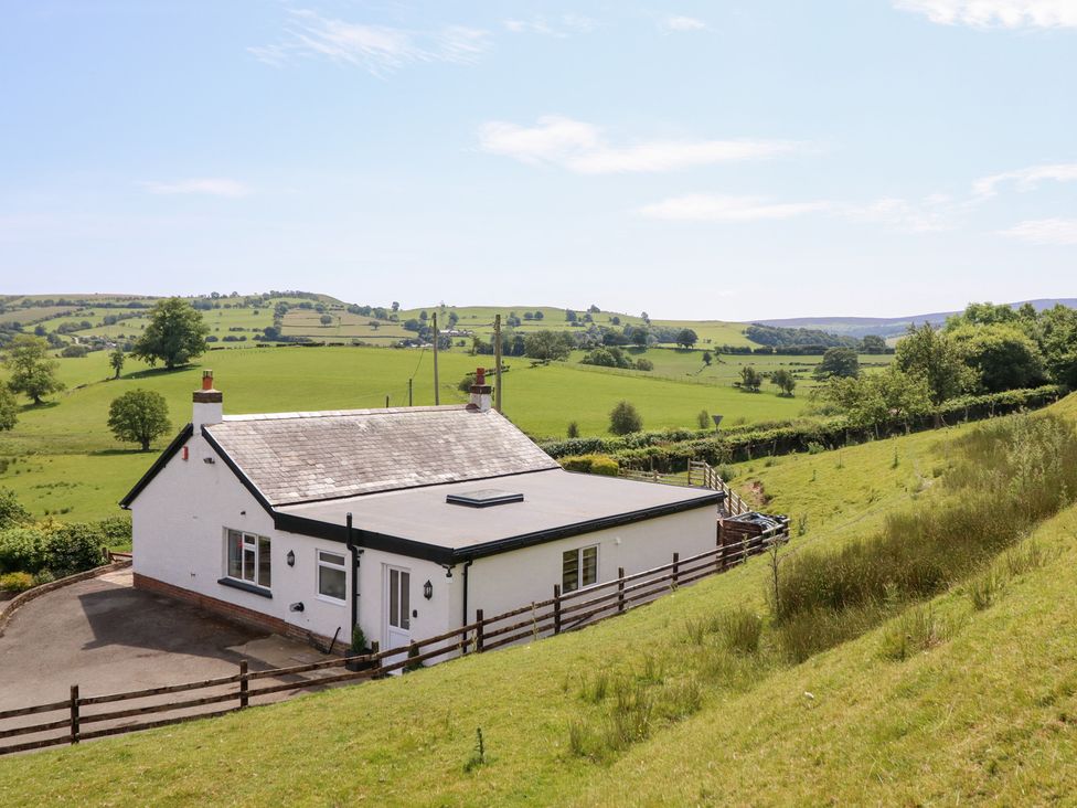 A house with fields and hills in the background at Bryn Bras in Corwen