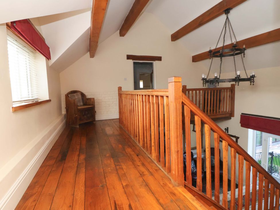 A landing area with wooden flooring and a chair at Home Farm St Asaph