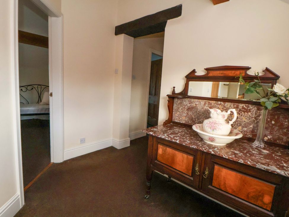 A wooden cabinet with a mirror and decorative items at Home Farm St Asaph