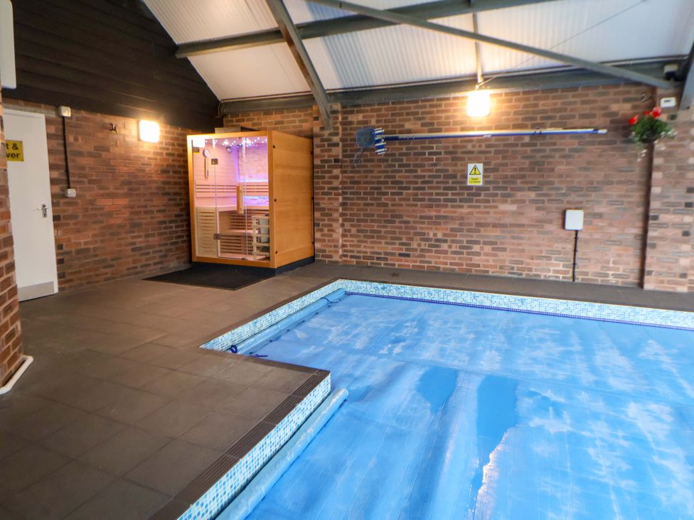 An indoor pool area with a sauna beside the pool at Home Farm St Asaph