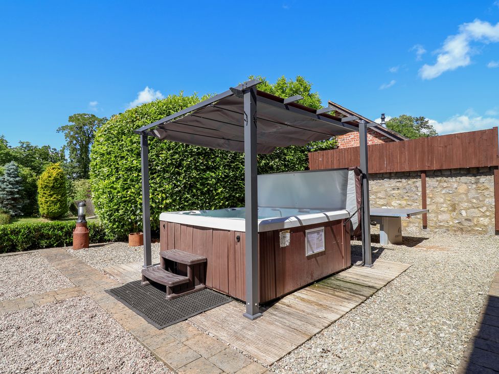 A hot tub under a canopy in a garden at Home Farm St Asaph