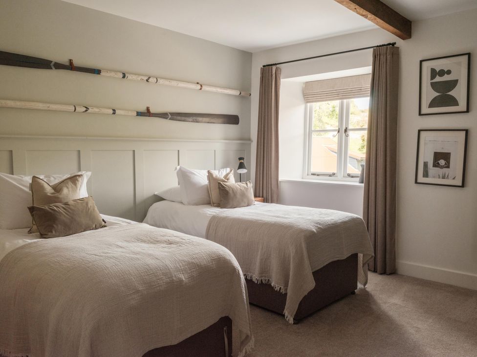 A bedroom with two beds and rowing oars on the wall at Lower Well Farm House in Totnes