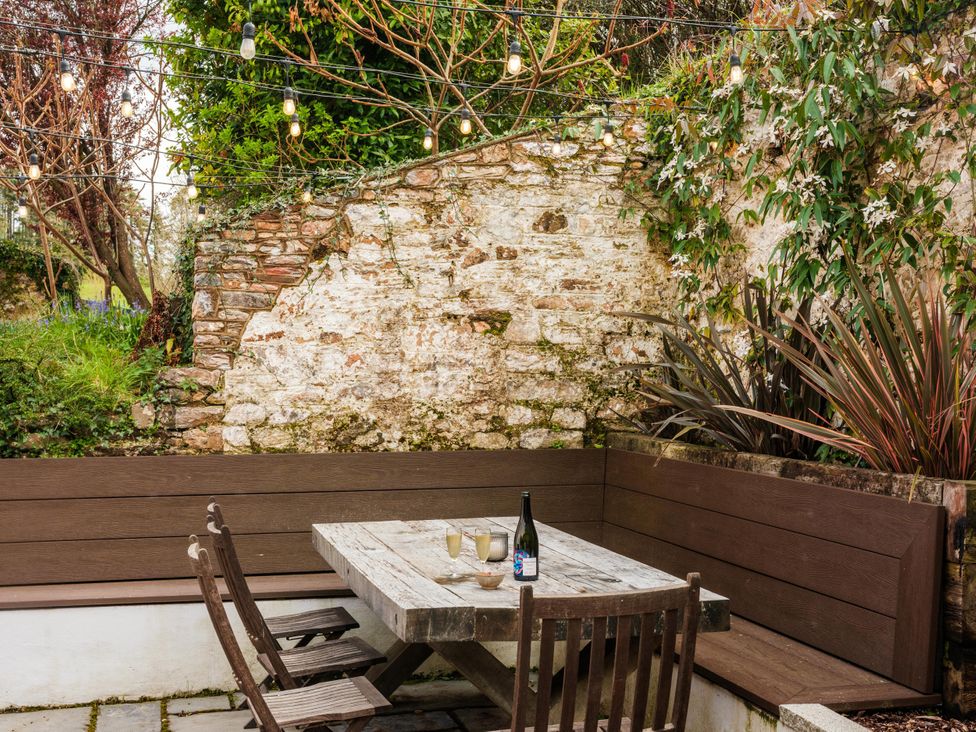 An outdoor seating area with a table and chairs at Lower Well Farm House in Totnes