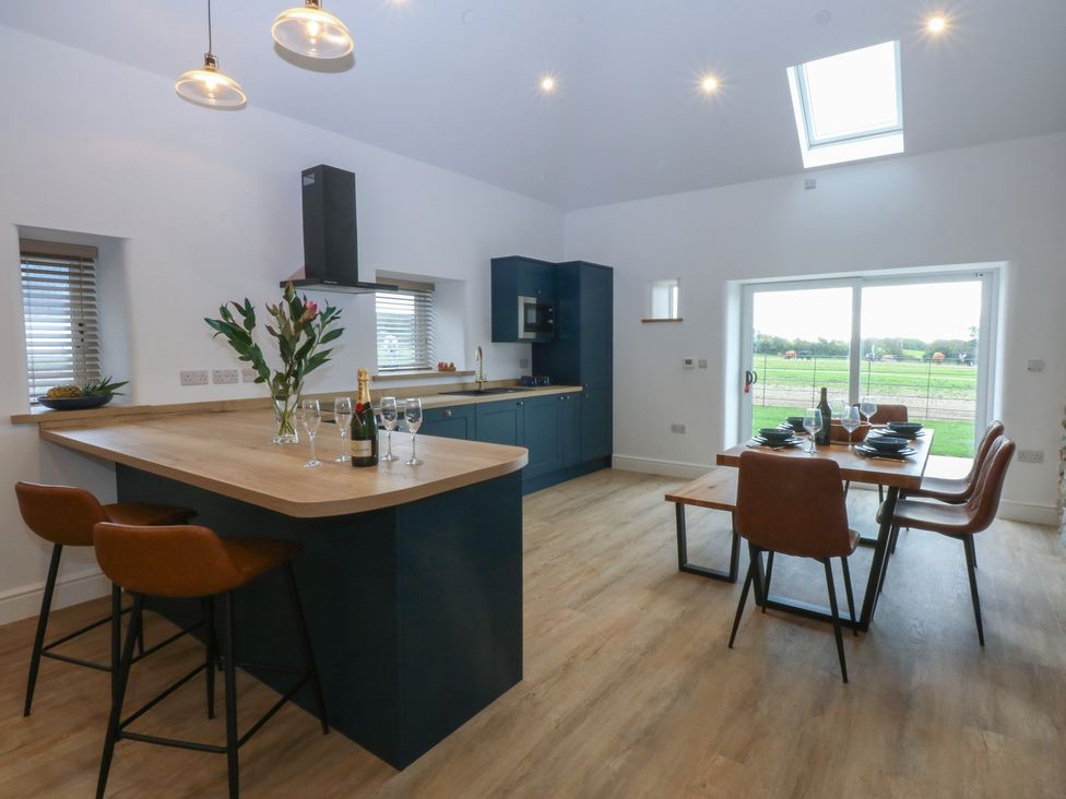 A kitchen with bar stools and dining table at Beudy