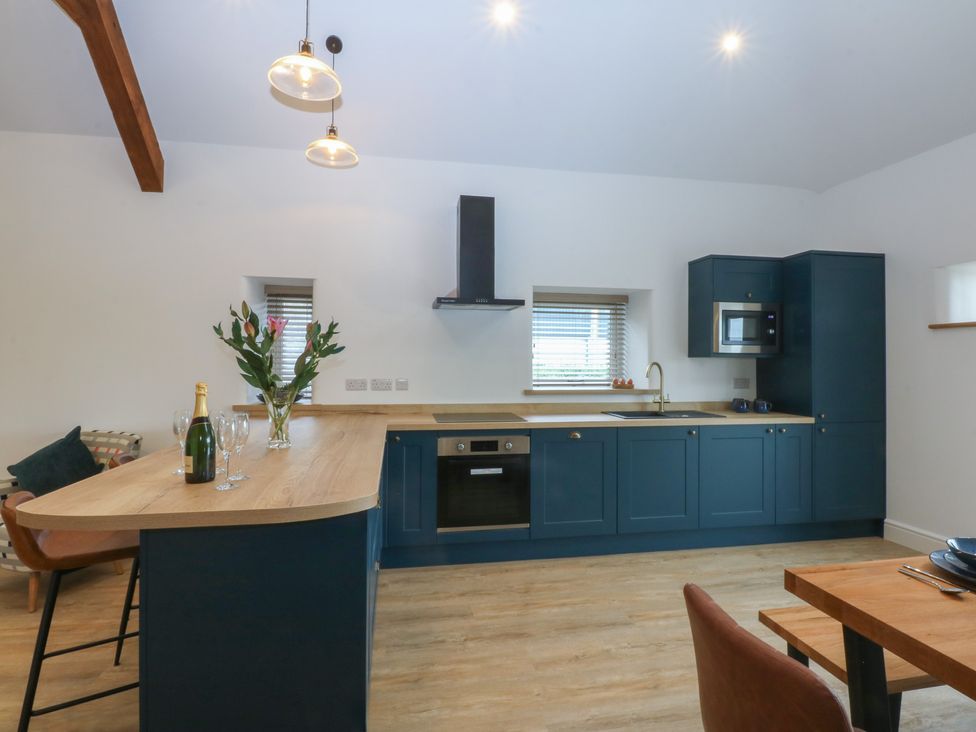 A kitchen with a counter and bar stools at Beudy