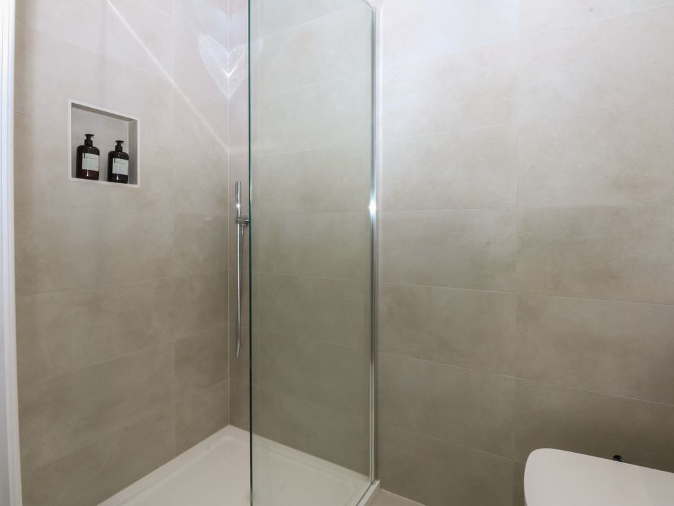 A shower with a glass screen and shelves at Beudy 