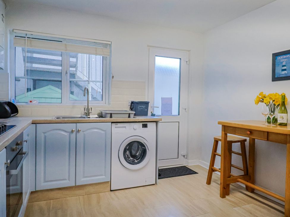 A kitchen with a washing machine and table at Sea Lovers in Exmouth