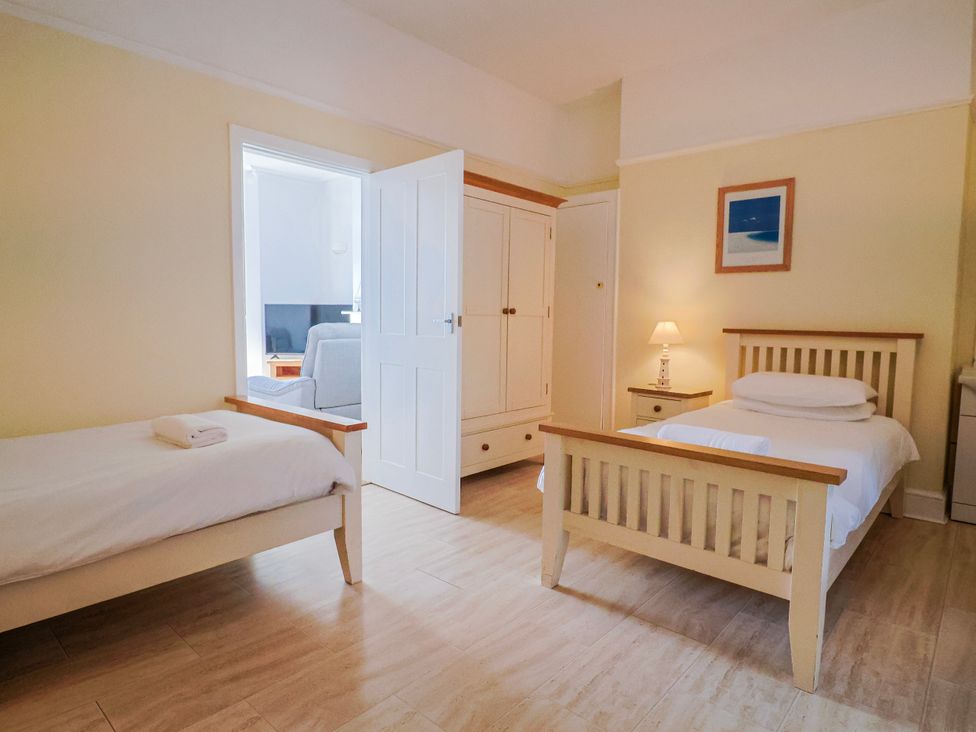 A bedroom with two beds, a nightstand and a wardrobe at Sea Lovers in Exmouth