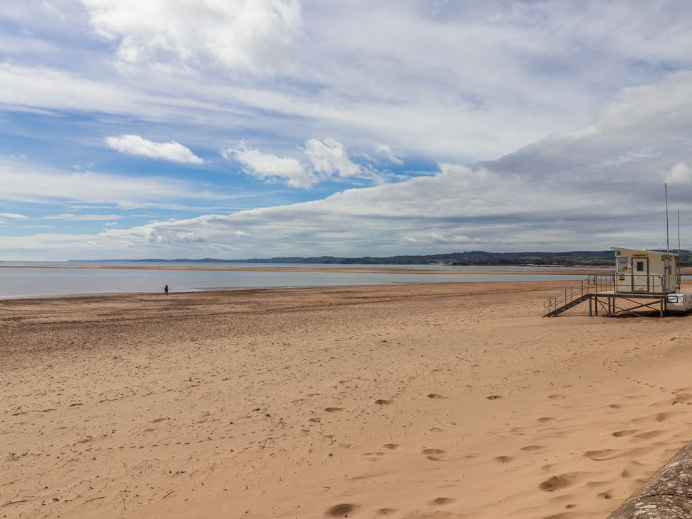A beach with a lifeguard station and a person walking at Sea Lovers in Exmouth