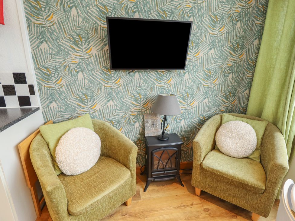 A living room with two armchairs and a TV at Seaside Retreat in Chapel Point near Chapel St Leonards