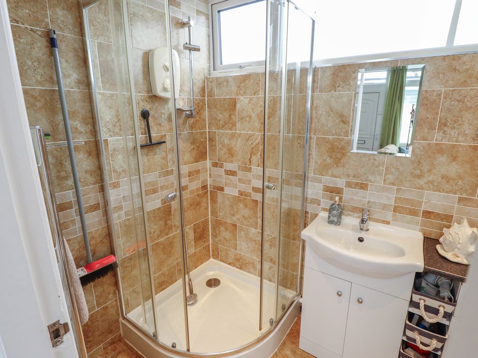 A bathroom with a shower, sink, and mirror at Seaside Retreat in Chapel Point near Chapel St Leonards