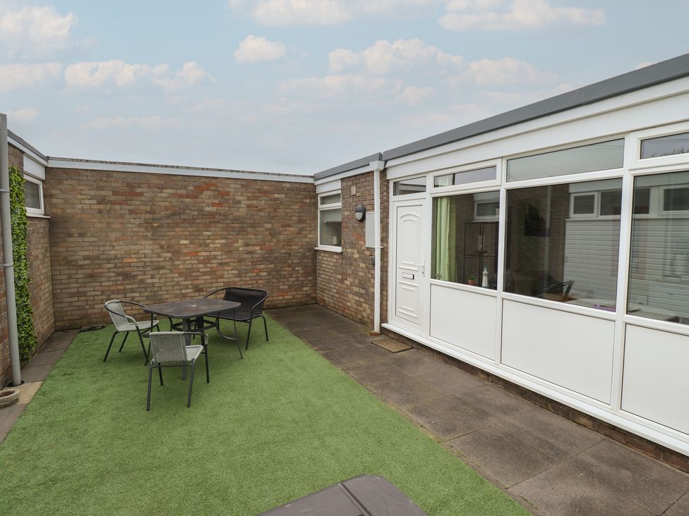 An outdoor patio area with seating and a door at Seaside Retreat Chapel Point near Chapel St Leonards