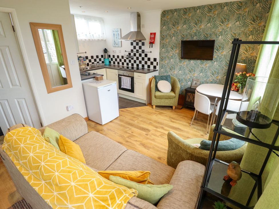 A living room with a sofa and kitchen area at Seaside Retreat near Chapel Point near Chapel St Leonards