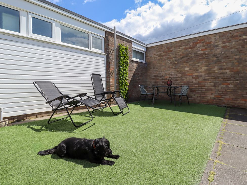 A garden with deck chairs and a table at Seaside Retreat in Chapel Point near Chapel St Leonards