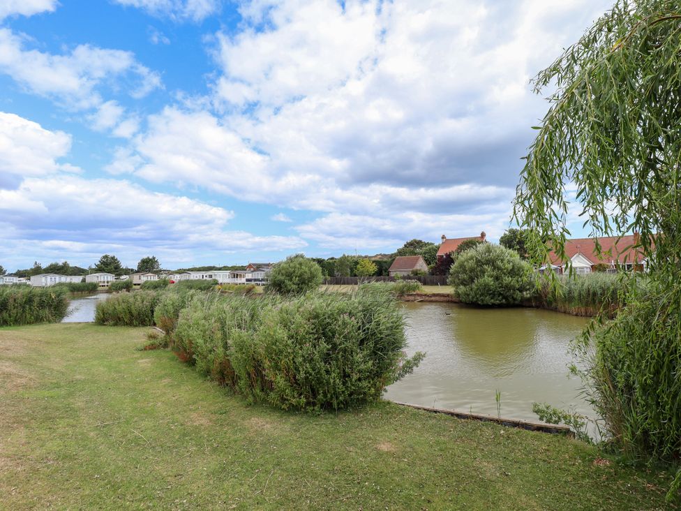 A view of water and grass with bushes and houses at Seaside Retreat near Chapel Point near Chapel St Leonards